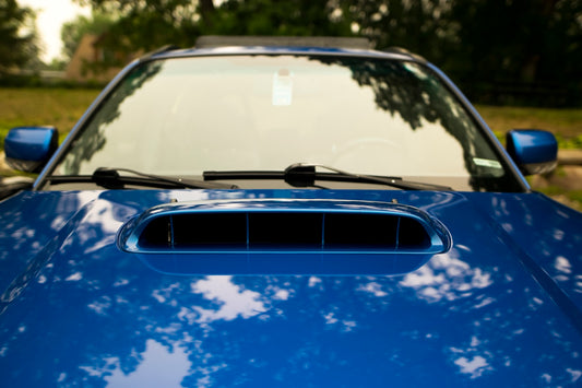 a close up of a blue car with trees in the background