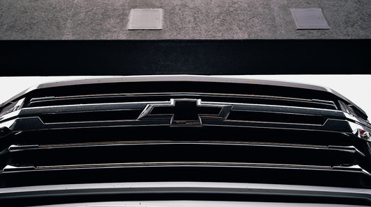 A chevrolet grill, close-up, gleaming in the light.
