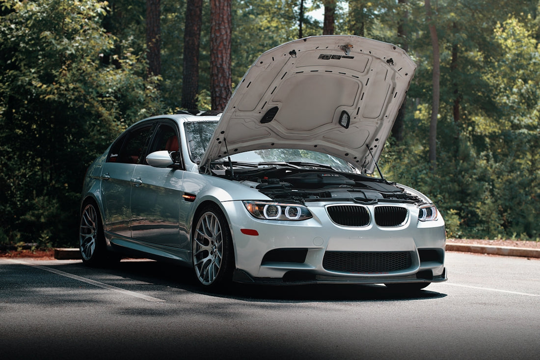 A silver BMW with its hood open.