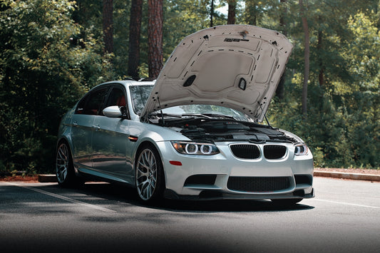 A silver BMW with its hood open.