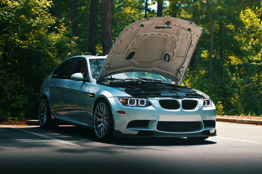 A silver car with its hood open.