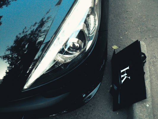 Black car parked next to a curb with bag